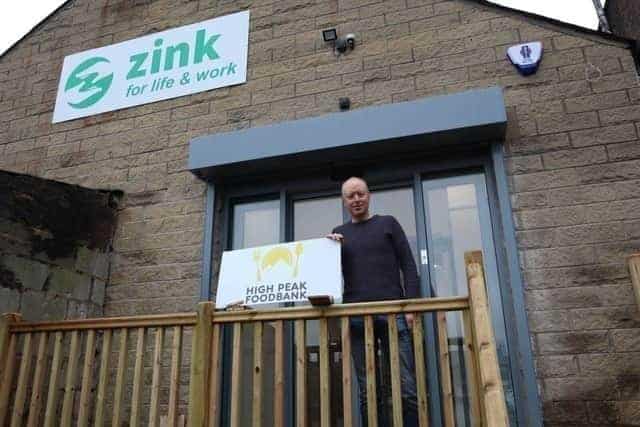 Paul holding a large cheque in front of Zink HQ